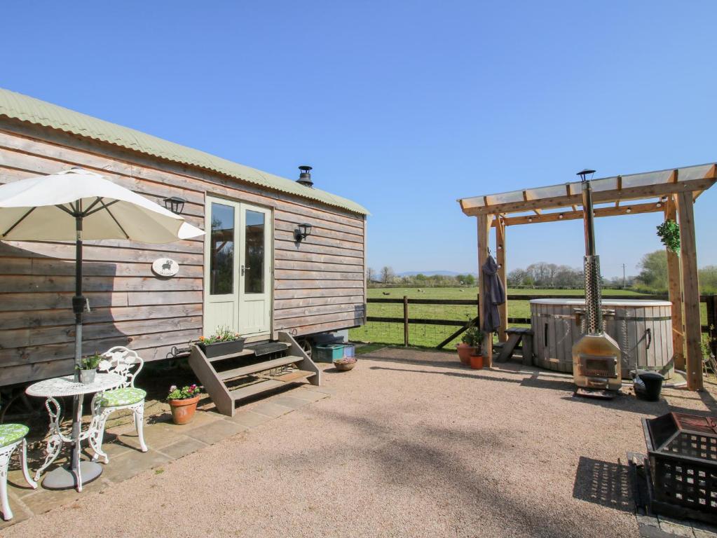 a house with an umbrella and a table and chairs at Balwen Shepherd's Hut in Montgomery