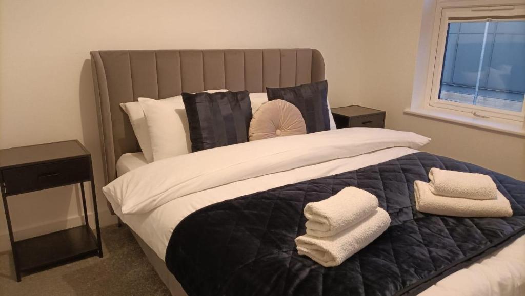 a bedroom with a large bed with towels on it at Cohost Partners 3 Bed Apartment in Warrington in Warrington