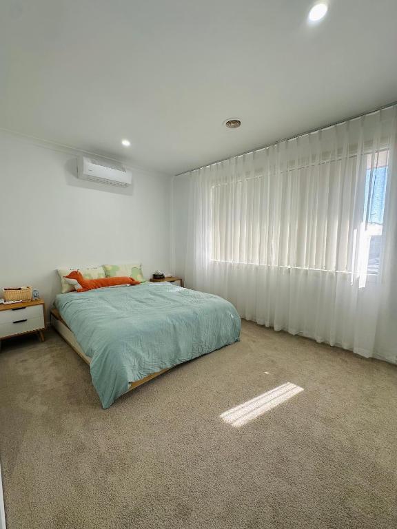 a white bedroom with a bed and a window at Central Nest at Caroline Springs in Caroline Springs