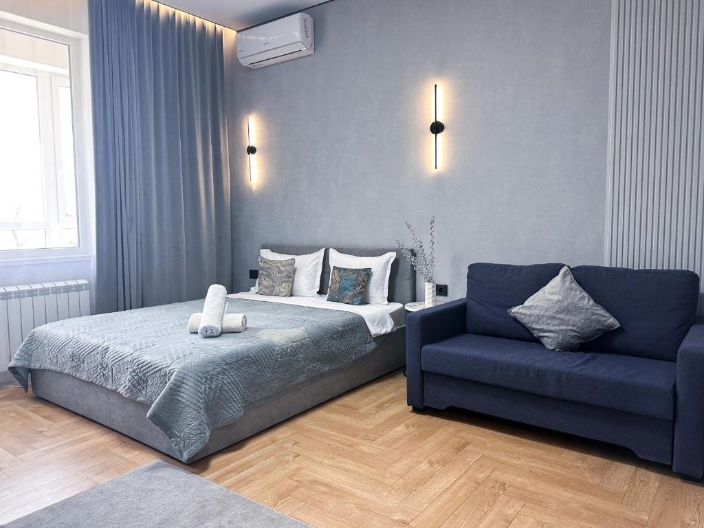 a bedroom with a bed and a blue couch at Современный отдых в сердце города in Almaty