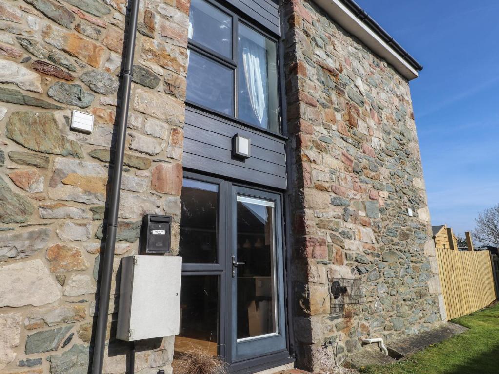 a brick building with a door and a window at 5 Stad Clynnog in Llanfairpwllgwyngyll