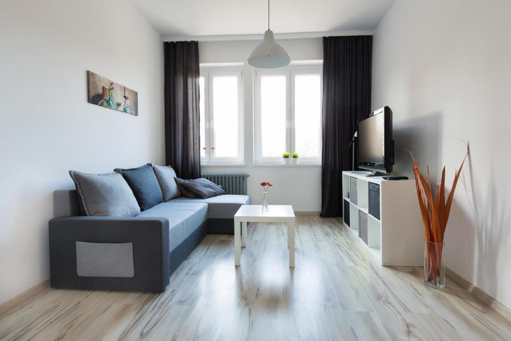 a living room with a blue couch and a tv at Apartament Wały Chrobrego in Szczecin