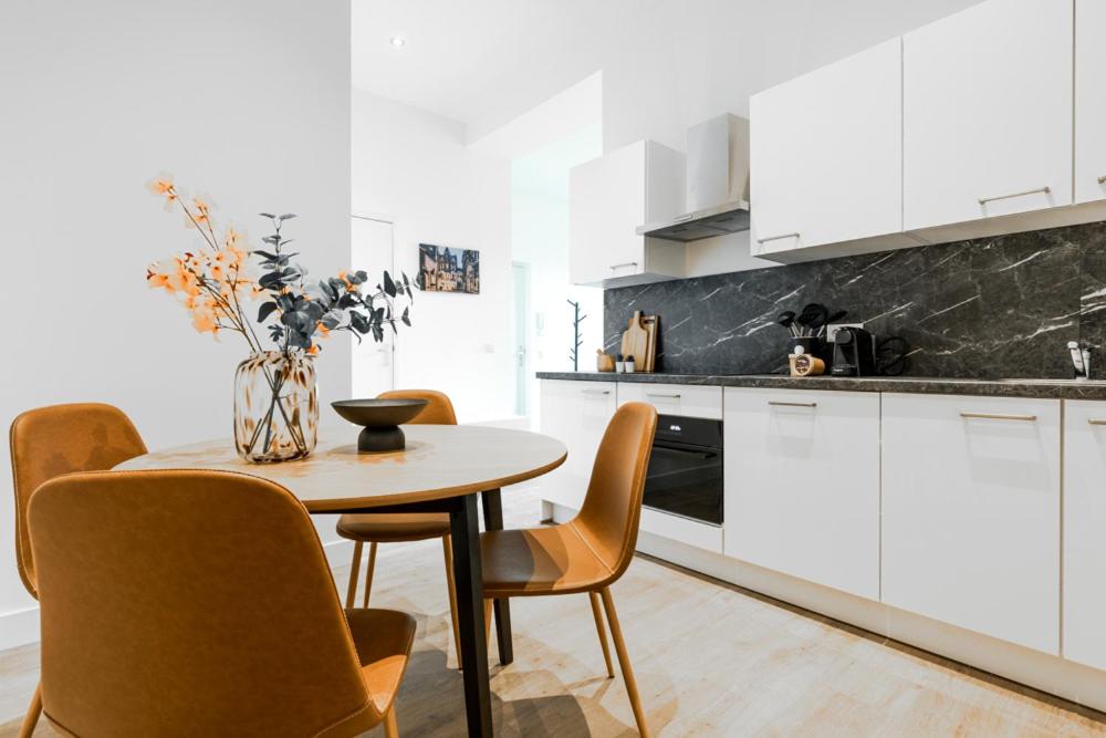 a kitchen with white cabinets and a table with chairs at Spacious home, 10 min from Efteling in Tilburg