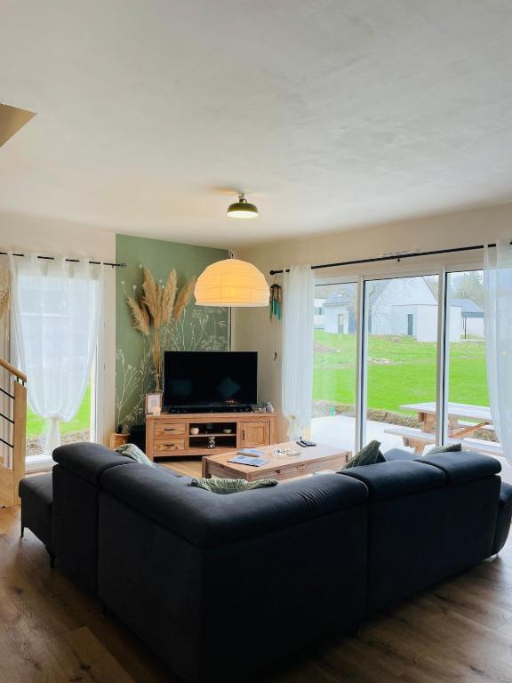 un salon avec un canapé noir et une télévision dans l'établissement Le Gite d'Almaju 3 étoiles, 3 chambres, 6 couchages, à Plestin-les-Grèves