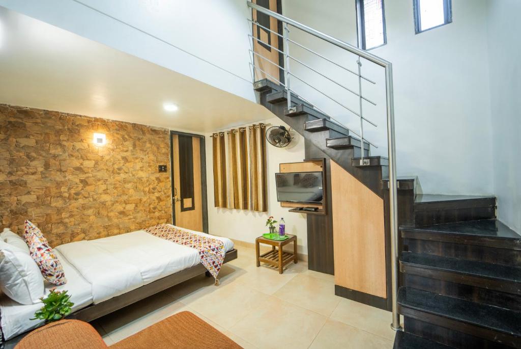 a small room with a bed and a staircase at The Sangam Hotel in Mahabaleshwar