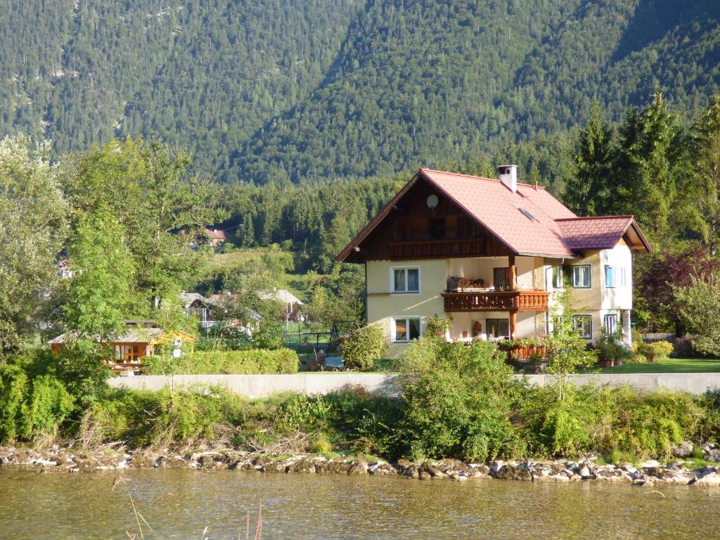 una casa junto al agua con montañas en el fondo en Haus Bergblick, en Obertraun