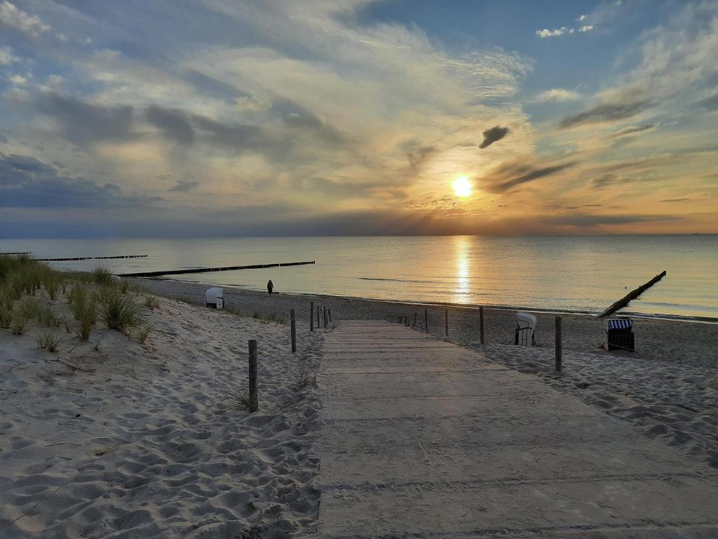 a path on a beach with the sunset in the background at Küstenbrise 2 in Graal-Müritz