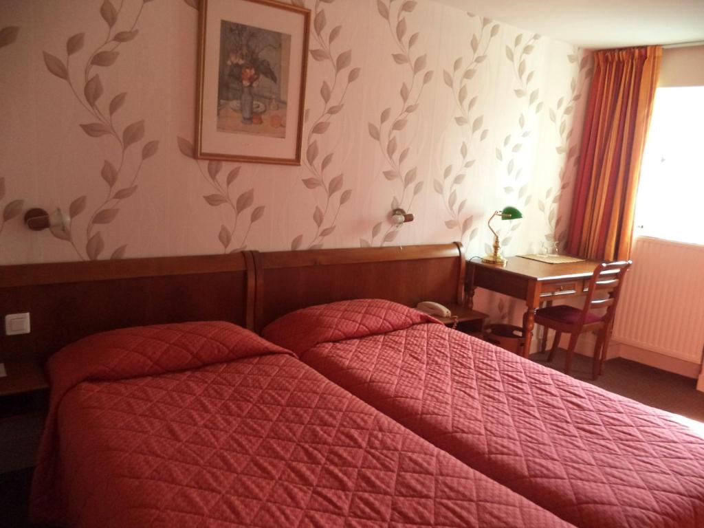 a bedroom with a bed with a red comforter at Cit&#39;Hotel Avallon Vauban in Avallon
