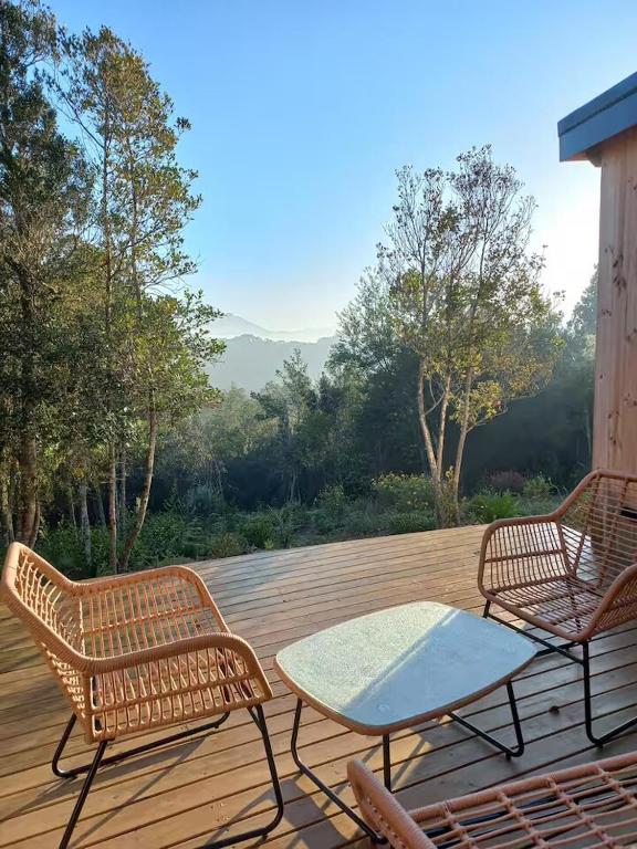 two wicker chairs and a table on a deck at FireFly Starry Woods Cabin in Keurboomstrand