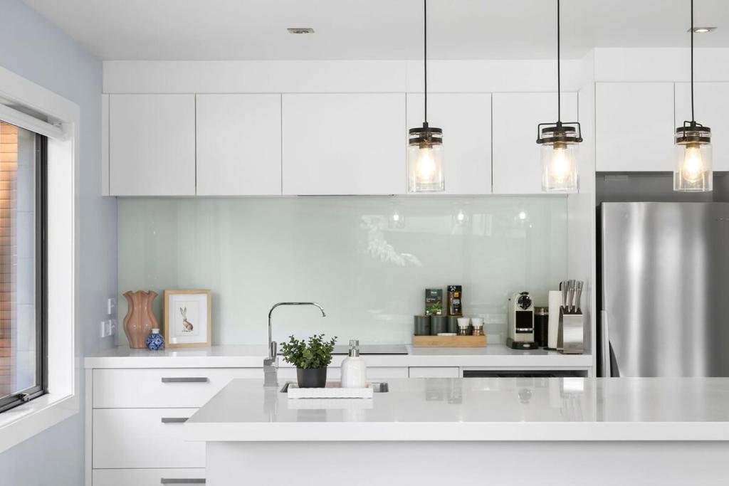 a white kitchen with a sink and a refrigerator at Wanaka Tree On Your Doorstep! in Wanaka