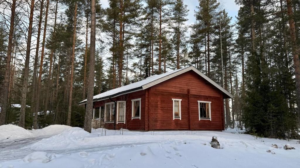 ein kleines Haus im Schnee in einem Wald in der Unterkunft Cozy Cottage in Kerimaa in Savonlinna