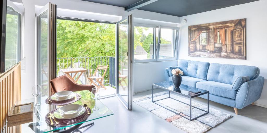 a living room with a blue couch and a glass table at Belnoir by BRIGHT in Augsburg