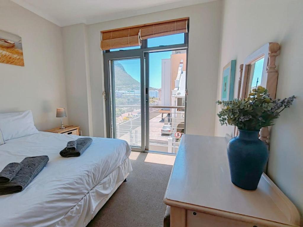 a bedroom with a bed and a vase on a table at The Waves Empire Apartment in Muizenberg