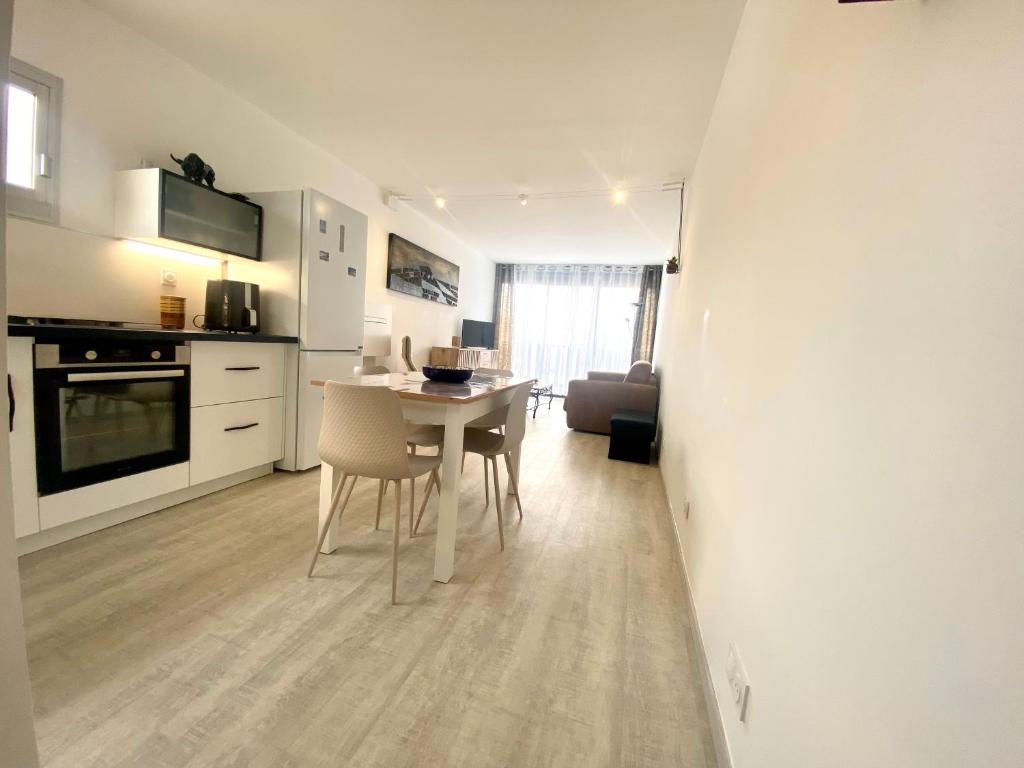 une cuisine et une salle à manger avec une table et des chaises dans l'établissement LE BOUCANET - APPARTEMENT CLIMATISÉ ENTIEREMENT RÉNOVÉ POUR 4 PERSONNES AVEC PARKING PRIVATIF, au Grau-du-Roi