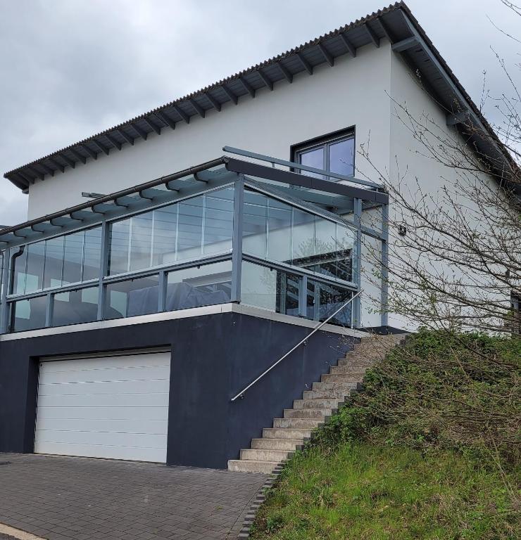 a large white house with glass windows and stairs at Moselanker de in Enkirch Mosel in Enkirch