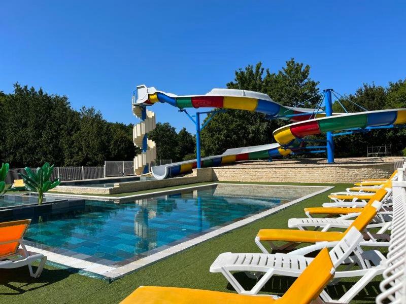 a swimming pool with chairs and a water slide at Camping Le Lizot - Aquatique Vacances in Saint-Mandé-sur-Brédoire