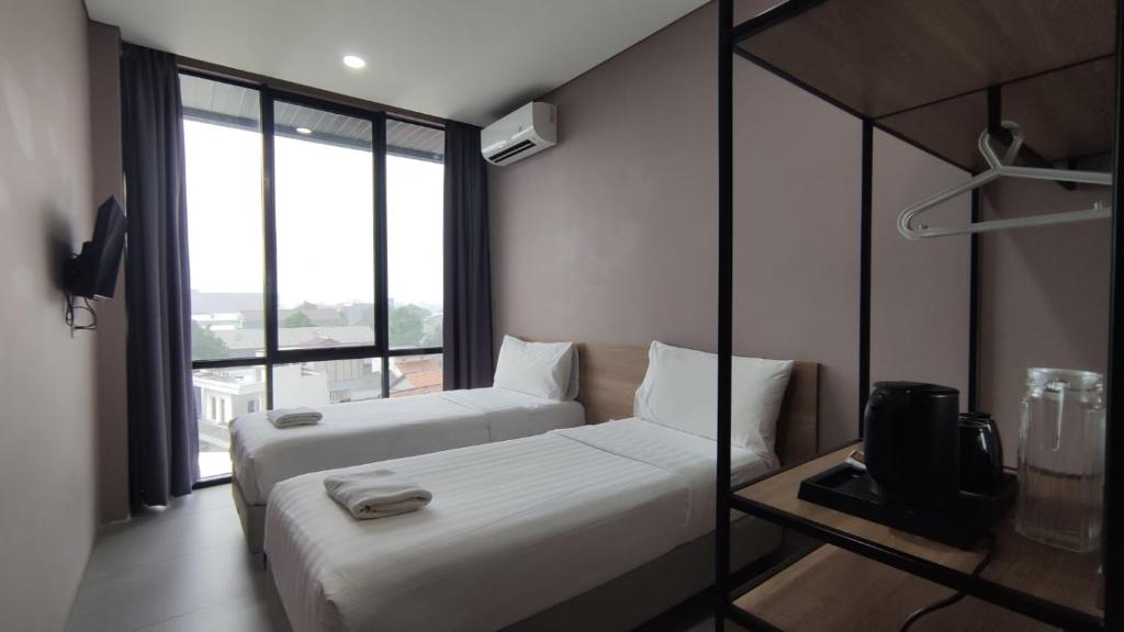 una camera d'albergo con due letti e una tv di VNC Alam Sutera Hotel Powered by Archipelago a Dongkal