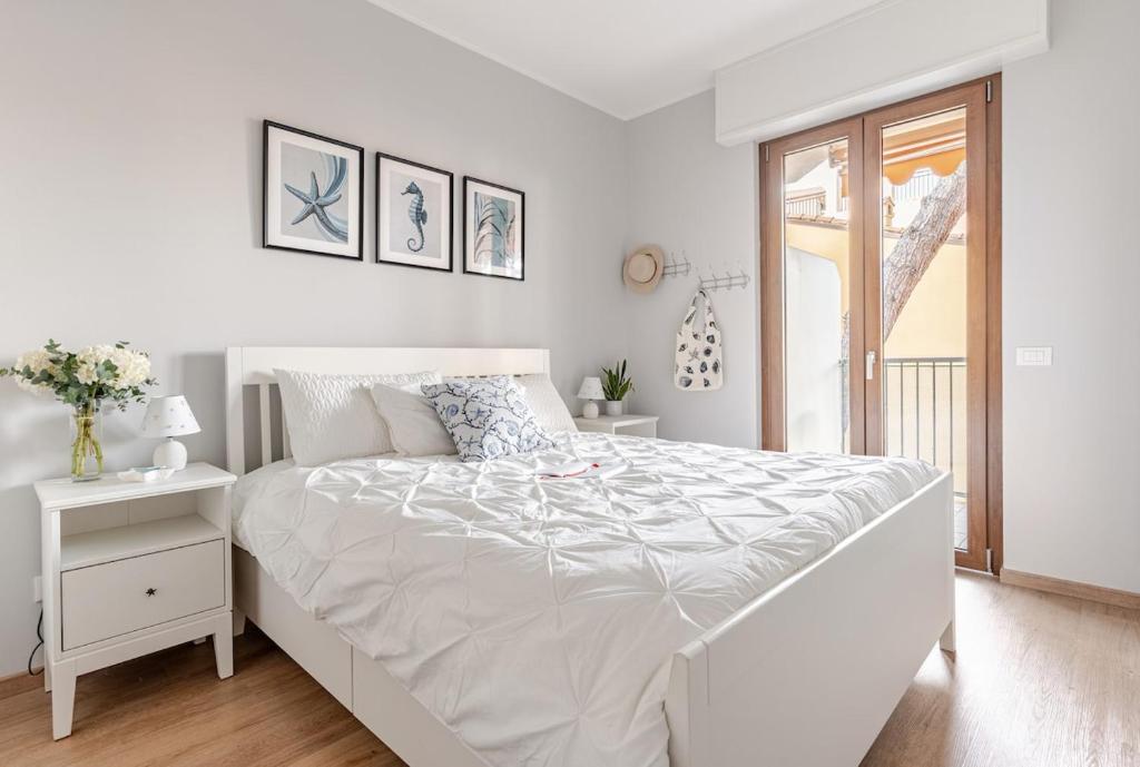 a white bedroom with a large bed and a window at TheKeyStudio, Stella Marina Suite in Bordighera