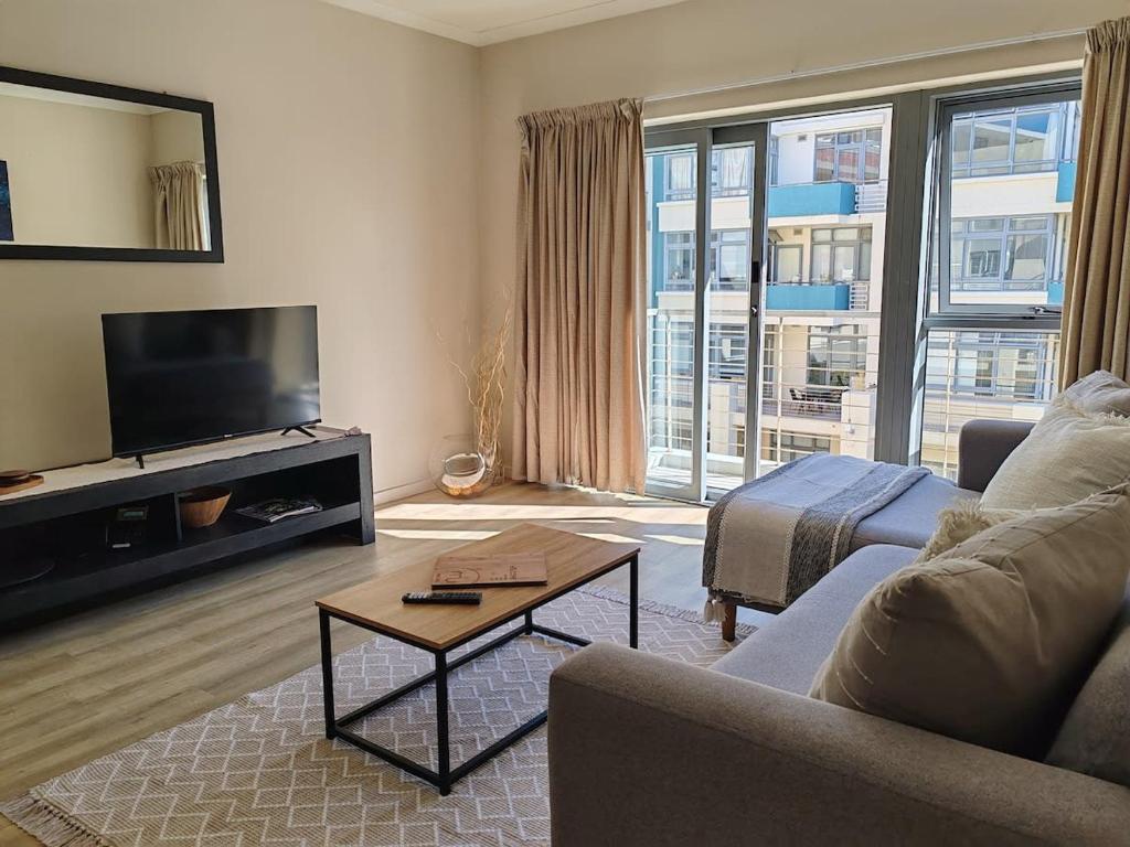 a living room with a couch and a tv at Beach Loft Empire Apartment in Muizenberg