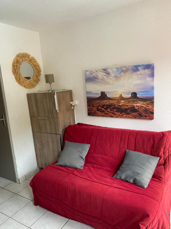 a red couch in a room with a painting on the wall at Le petit soleil in Lamalou-les-Bains