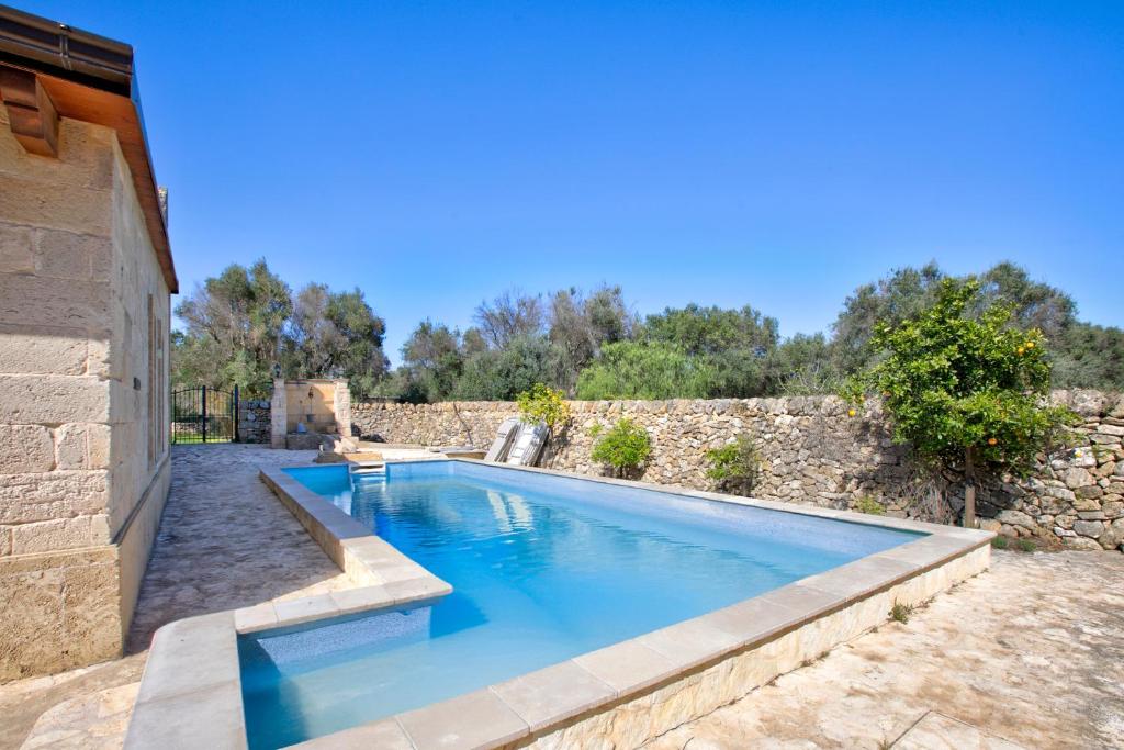 basen przed kamienną ścianą w obiekcie Masseria Antoglia Rooms w mieście Villa Castelli
