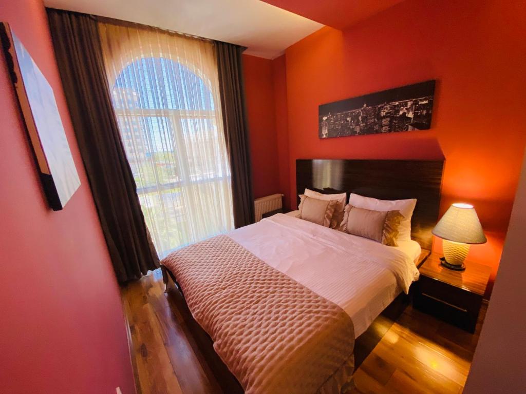 Schlafzimmer mit orangefarbenen Wänden und einem Bett mit Fenster in der Unterkunft Royal Loft Suit in Antalya