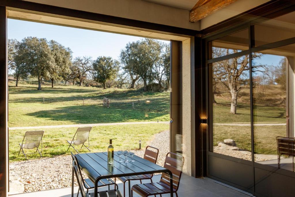 une terrasse couverte avec une table et des chaises donnant sur un champ dans l'établissement La Bergerie de Fenouillet, domaine AB en Pic Saint Loup, à Vacquières