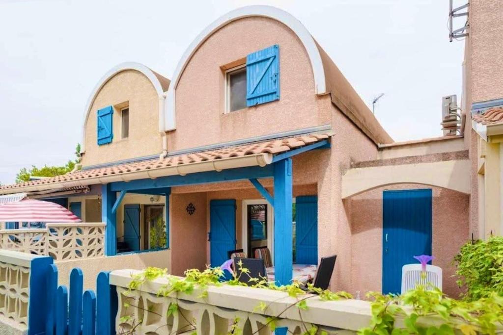 une maison avec des portes bleues et une clôture dans l'établissement Maison 3 pièces - Gruissan GA090-002, à Gruissan