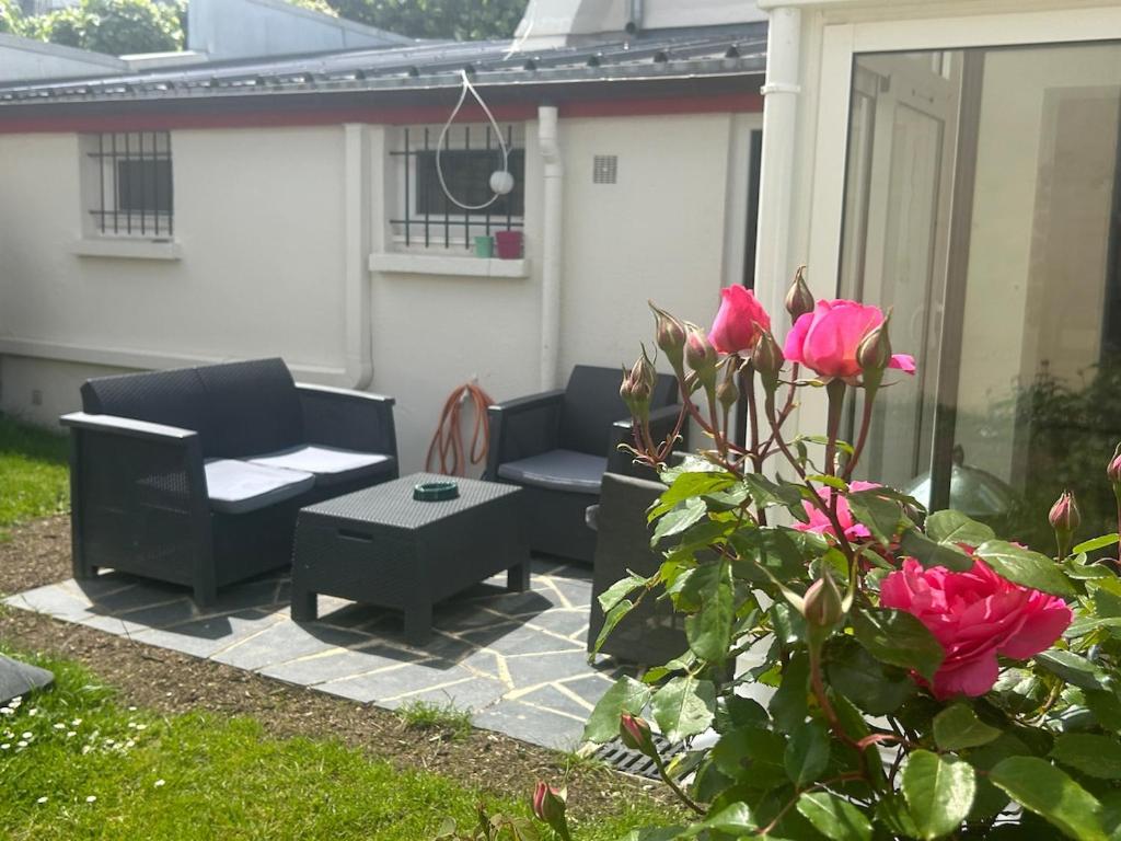 une terrasse avec 2 chaises, une table et des roses dans l'établissement Maison 3 chambres hyper centre, à Cabourg