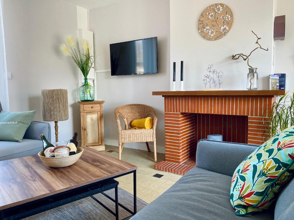 a living room with a couch and a fireplace at À La Mollière in Cayeux-sur-Mer