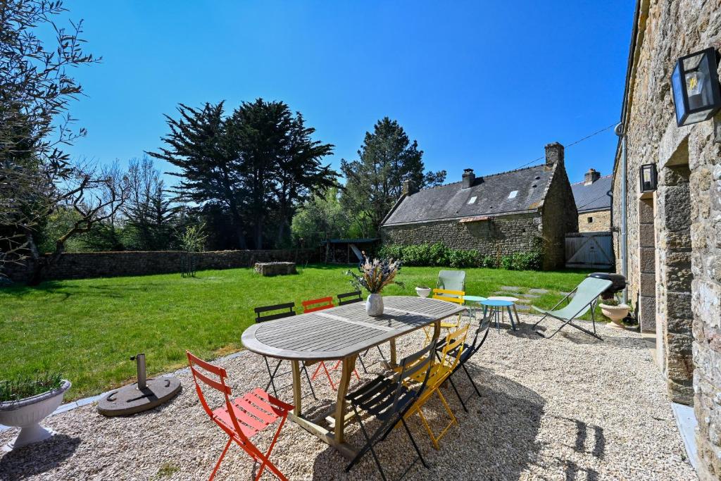 un patio avec une table et des chaises dans une cour dans l'établissement Longère Kerinis - Maison avec grand jardin, à Locmariaquer