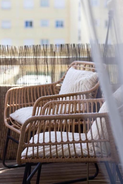 - deux chaises en osier avec des oreillers blancs sur le balcon dans l'établissement Joli appartement 2 pièces proche plage, à Fréjus