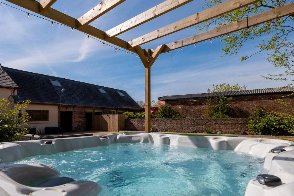 a hot tub in a backyard with a wooden pergola at Abbey Farm House - Pet Friendly in Ormskirk