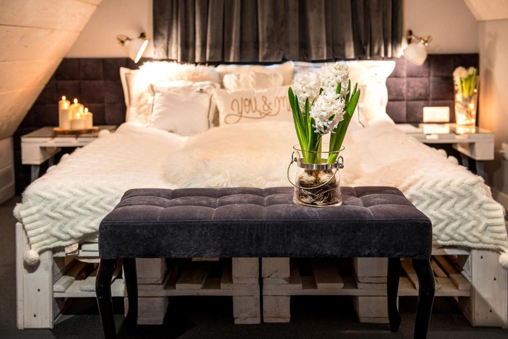 Una cama con una mesa con un jarrón de flores. en Silverton - blisko stoku, sauna, mini siłownia, przyjazny rodzinom, en Białka Tatrzanska
