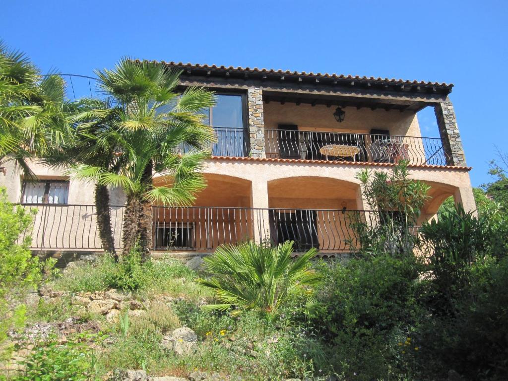 une maison avec un balcon et un palmier dans l'établissement Casa Paulette, à Cavalaire-sur-Mer