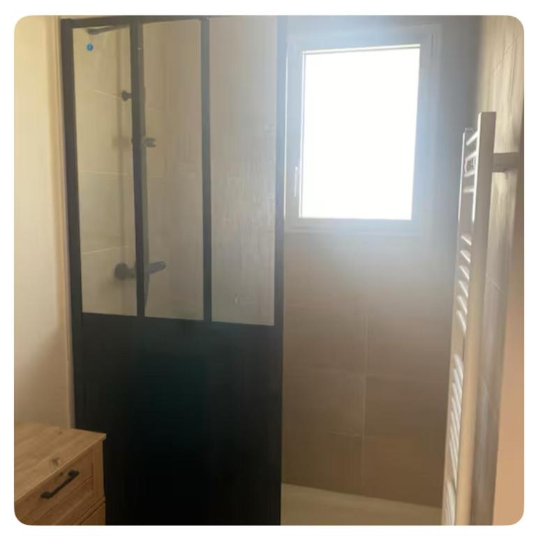 La salle de bains est pourvue d'une douche en verre et d'une fenêtre. dans l'établissement Maison paisible, à Tréméoc