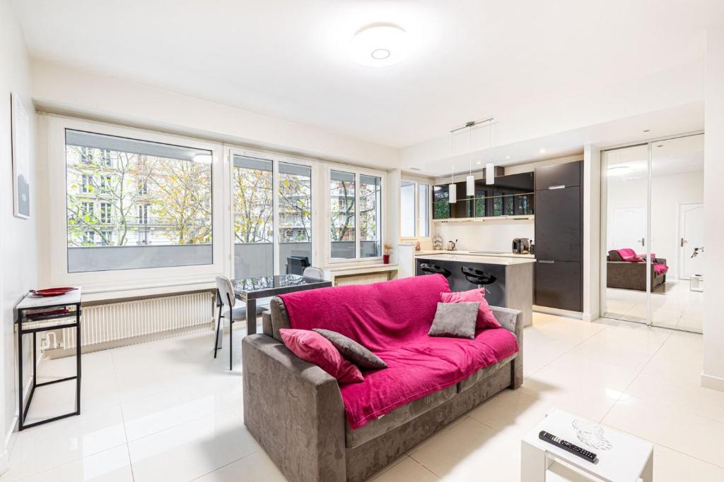 un salon avec un canapé rose et une cuisine dans l'établissement GuestReady - Bright charm with a terrace, à Paris