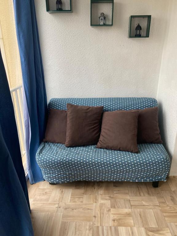 un divano blu con due cuscini marroni in una stanza di Appart Gwen a Gruissan