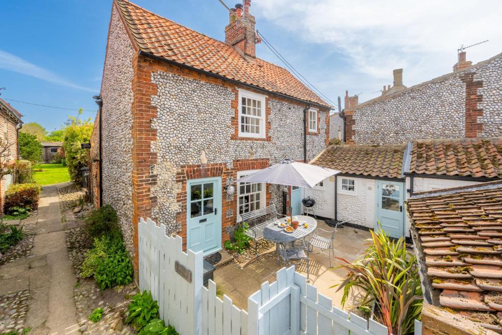 an exterior view of a brick house with a white fence at Yew Tree Cottage in Blakeney