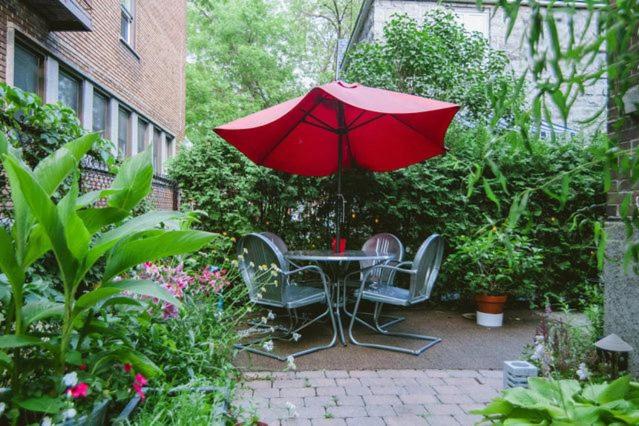 a table and chairs with a red umbrella in a garden at L'Adresse Botanique - Studio in Montréal