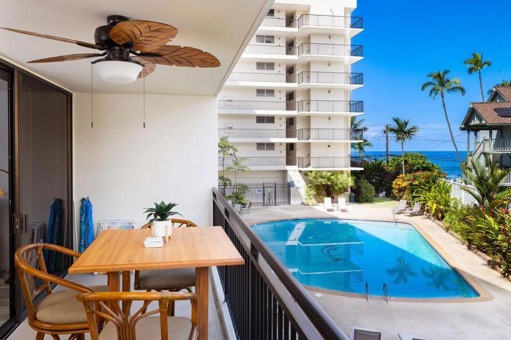 a balcony with a table and a swimming pool at Kona Alii#211 in Kailua-Kona