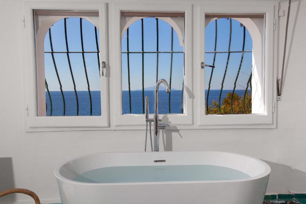 a bath tub in a bathroom with three windows at Estate4home - Suite Bonview in Massa Lubrense