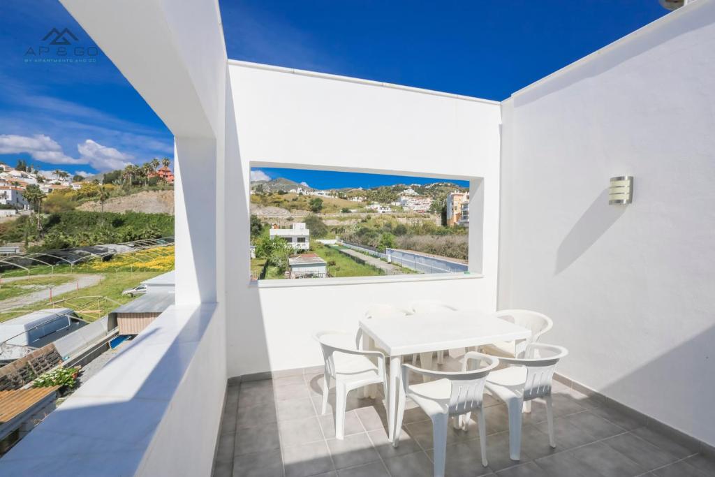 een witte eetkamer met een tafel en stoelen en een groot raam bij House Beach Park in La Herradura