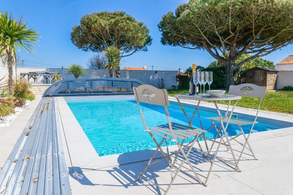a pool with two chairs and a table next to it at magnifique villa avec piscine - 8 personnes - paracou in La Chaume