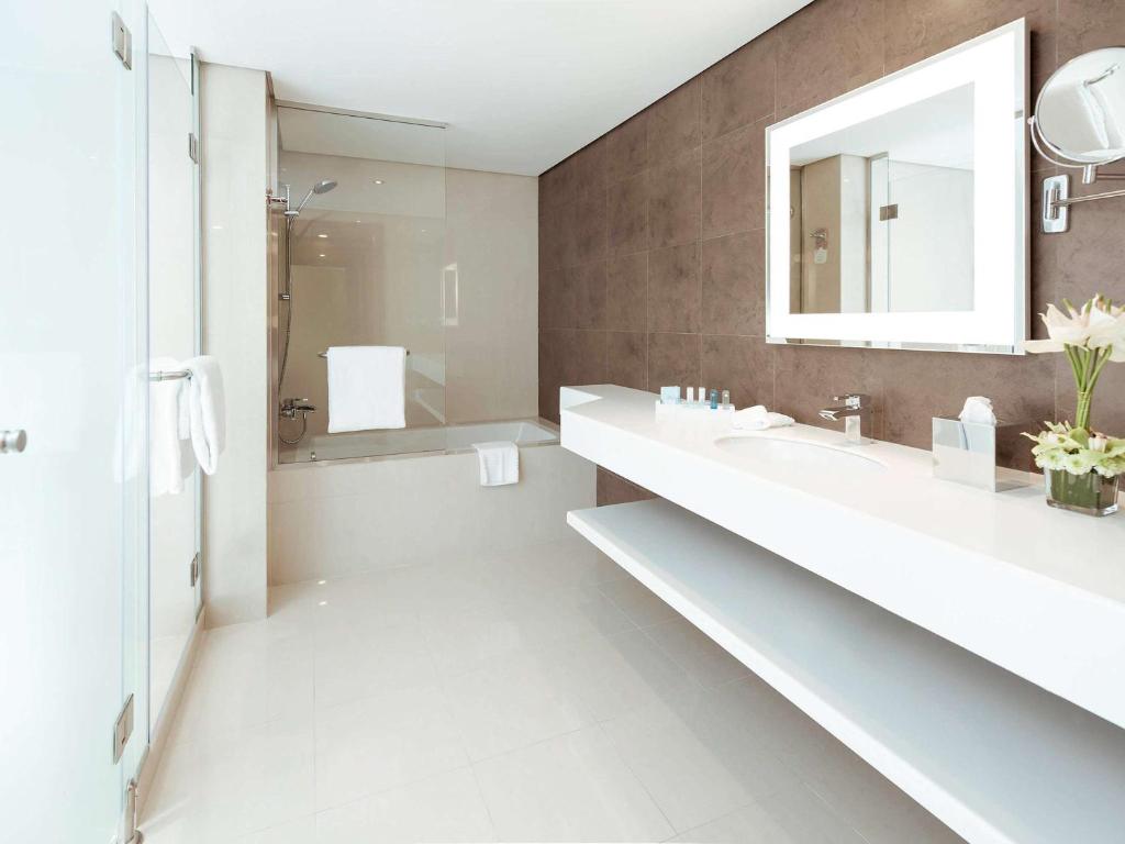a white bathroom with a sink and a mirror at Novotel Fujairah in Fujairah