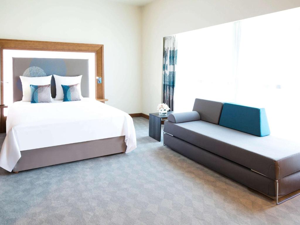 a bedroom with a bed and a couch at Novotel Fujairah in Fujairah