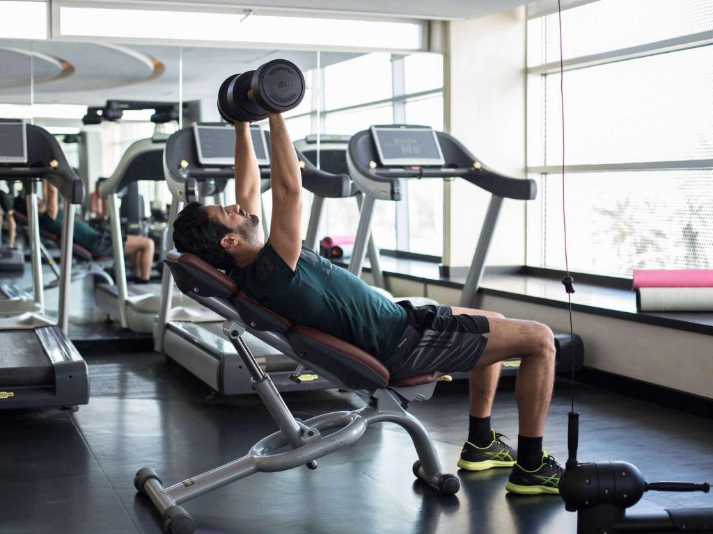 a man is lifting weights in a gym at Sofitel Casablanca Tour Blanche in Casablanca