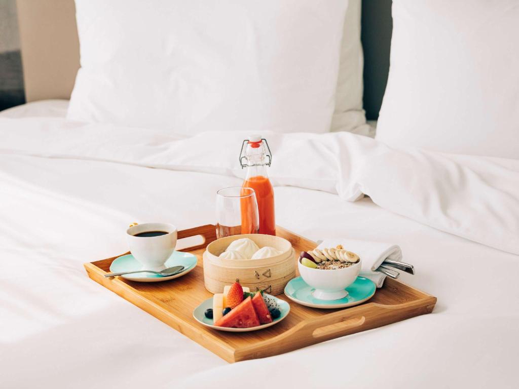 a tray with cups of coffee and fruit on a bed at Pullman Paris Roissy Cdg Airport in Roissy-en-France