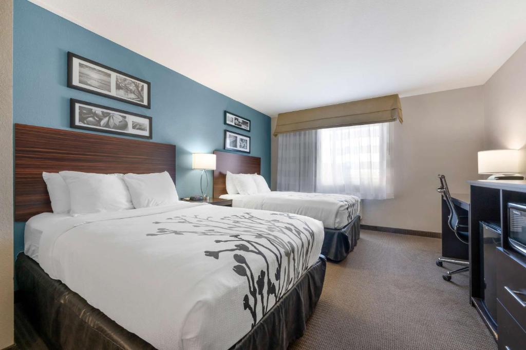 a hotel room with two beds and a television at Sleep Inn & Suites Hays I-70 in Hays