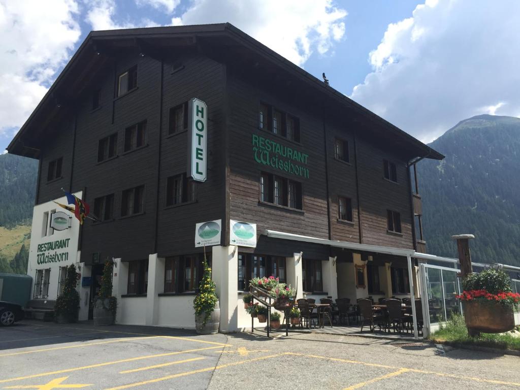 een groot gebouw met een bord aan de zijkant bij Hotel Weisshorn in Ritzingen